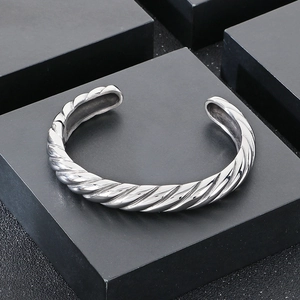 Détail macro du motif câble torsadé argenté sur le bracelet jonc en acier inoxydable