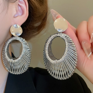 Gros plan d'un mannequin portant des boucles d'oreilles ovales tissées en velours argenté