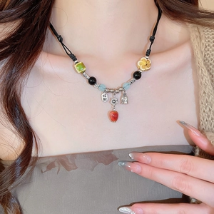 Detail of beaded necklace with ceramic pendant and silver lucky charm on black cord