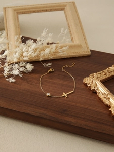 Close-up of golden cross bracelet with zircon stone on a rustic wooden display