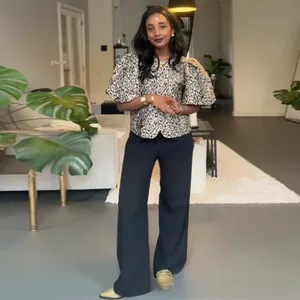 Detail of leopard print blouse with puff sleeves and dark wide-leg pants on a model