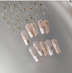 Macro detail of M-332 gold floral nail stickers on pink French tip press-on nails