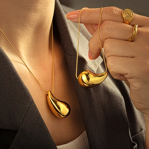 Polished 18k gold plated drop necklace and spiral textured ring set on a fashion model