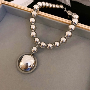 Detailed macro view of polished silver bead necklace with large mirror pendant on velvet tray