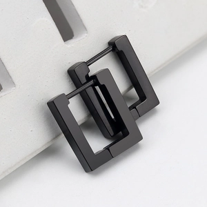 Close-up of matte black stainless steel rectangular geometric hoop earrings on grey stone