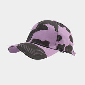 Side view detail of purple and black cow print canvas baseball cap with curved brim