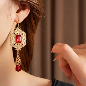 Detailed shot of vintage gold earrings with large red ruby and small sparkling crystals