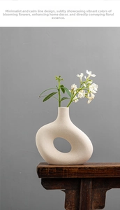 Detail of matte cream ceramic vase with irregular circular hollow design and flowers