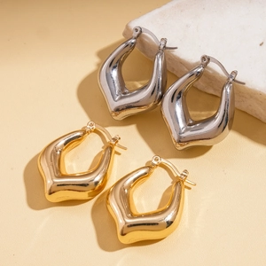 Polished gold and silver U-shaped hoop earrings on elegant marble and leather display