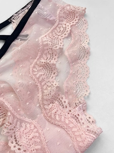 Detailed view of pink lace and sheer mesh fabric with black elastic trim on panties