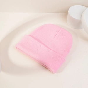 Vue détaillée du bonnet en maille rose avec revers sur fond minimaliste moderne