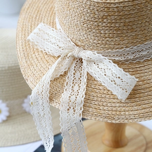 Women's summer straw sun hat with elegant white lace ribbon bow for beach vacations