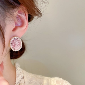 Detailed close-up of vintage cameo earring with pink portrait and faux pearl border