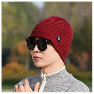 Close-up of wine red ribbed knit beanie featuring an NY&JA side label in an outdoor setting