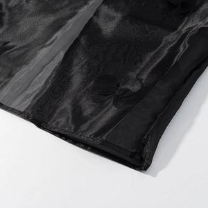Détail macro du tissu en organza noir avec broderie florale 3D et texture en maille fine