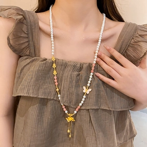 Detail einer Vintage-Goldperlenkette mit Lotus-Anhänger und Schmetterling am Modell