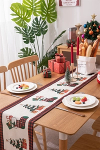 Detail of Christmas table runner with red plaid border and festive tree pattern