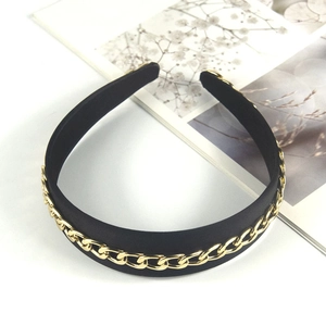 Detail of black velvet headband featuring a prominent gold chain link decorative overlay