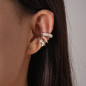 Close-up of three silver irregular geometric ear cuffs worn on model ear