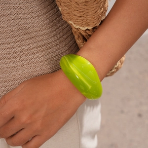 Close-up of a wide bright green acrylic bangle bracelet worn by a model in a summer style