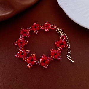 Détail macro du collier de perles florales rouges avec fermoir mousqueton doré et chaîne