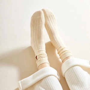 Close-up of cream knitted ribbed socks with cute brown bear embroidery detail