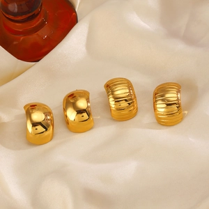 Golden C-shaped heart stud earrings with smooth and striped textures on beige silk