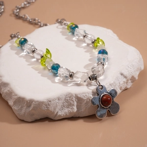 Détail du collier avec perles de verre bleues et pendentif fleur en argent ciselé