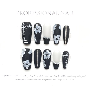Detail of press-on nails with daisy hand-paint, pearls and silver chains on white