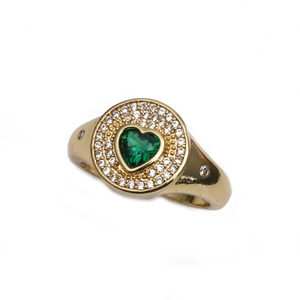 Bague coeur dorée avec pierre précieuse verte et zircons blancs sur fond blanc