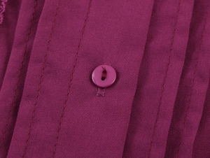 Dettaglio macro del tessuto viola con bottone e cuciture parallele decorative su abito