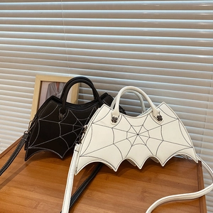 Detail view of black and white bat-wing purses with spiderweb stitching and cross decor
