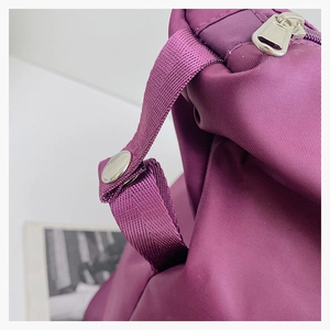 Detail of purple nylon travel bag showing silver snap buttons and metal zipper hardware