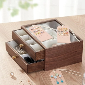 Deep brown wooden jewelry organizer with glass lid and drawers on wood tabletop
