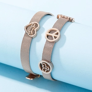 Rose gold mesh watch band bracelets with heart and peace sign charms on blue stand