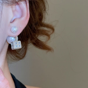 Nahaufnahme eines Silberperlenohrrings mit glitzerndem quadratischem Zirkonia-Anhänger