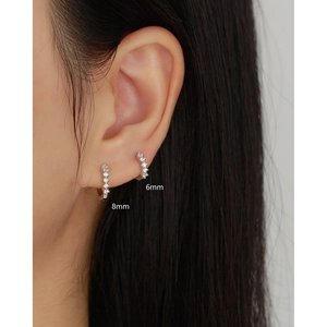 Detail of 6mm and 8mm silver hoop earrings with sparkling stones shown on ear