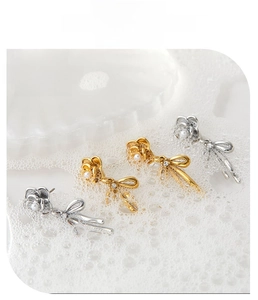 Macro shot of 316L stainless steel camellia bow earrings with small pearls in gold and silver