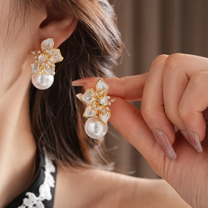 Detail of flower pearl earrings with gold plating and zircon center on model