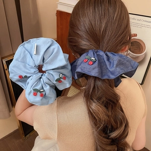 Close-up of cherry embroidery and pearl accents on large blue fabric scrunchies