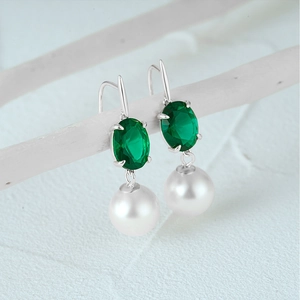 Detailed close-up of emerald green gemstone and white pearl on twisted silver ear wire