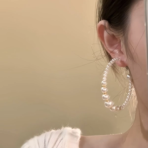 French vintage gold C-shape hoop earrings with large pearls on a female model