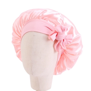 Dettaglio della cuffia da notte in raso rosa con fiocco su testa di manichino