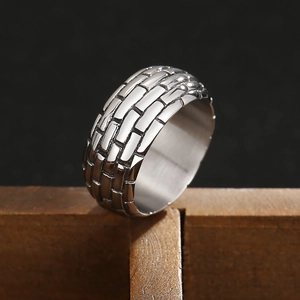 Men's wide silver titanium ring with brick texture on dark wood background