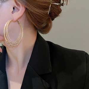 Close-up of layered golden multi-hoop earrings worn by a model in a black suit
