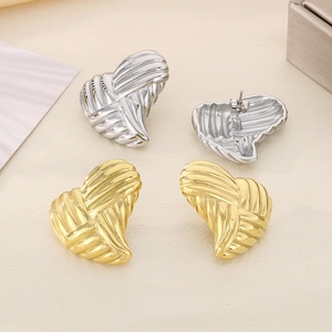 Detailed view of 18K gold and silver heart earrings with pearl inlay on soft fabric