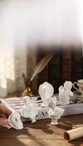 Classical Greek style resin mini bust statues on a vintage desk with retro books and props
