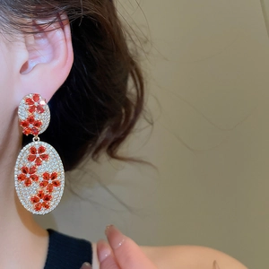 Close-up of vintage gold-tone oval drop earrings with red flower crystals on model