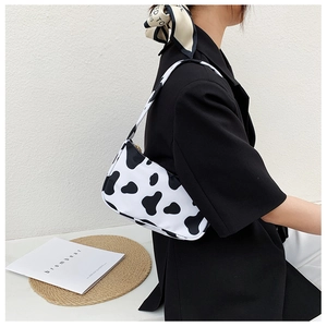 Detail view of stylish cow print shoulder bag with crescent shape on a model