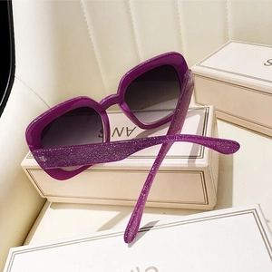 Detail of purple square oversized sunglasses featuring a glittery frame and gradient lenses